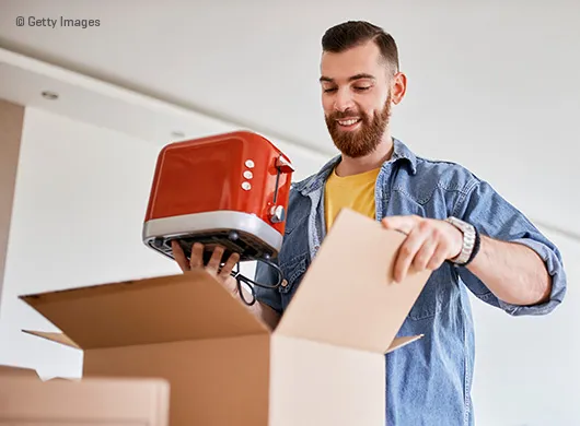 Man neemt broodrooster uit verhuis doos